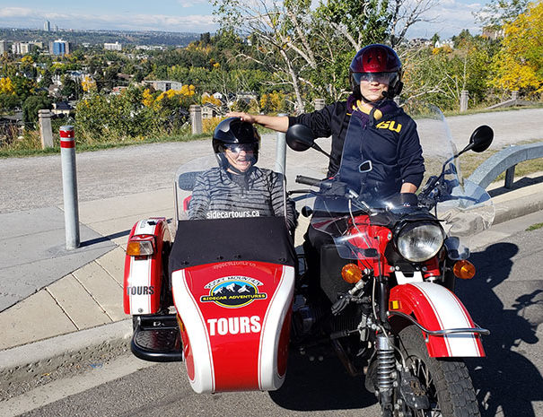 Rocky Mountain Sidecar Adventures Calgary Sightseeing Tour customers posing in bike and sidecar