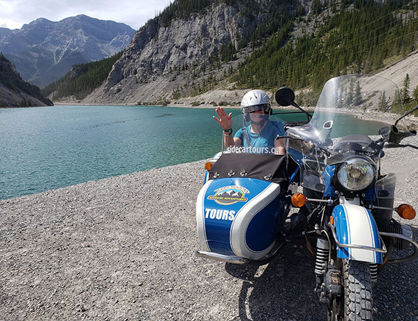 Rocky Mountain Sidecar Adventures Triple C Tour customer posing in front of beautiful Rocky Mountain Lake