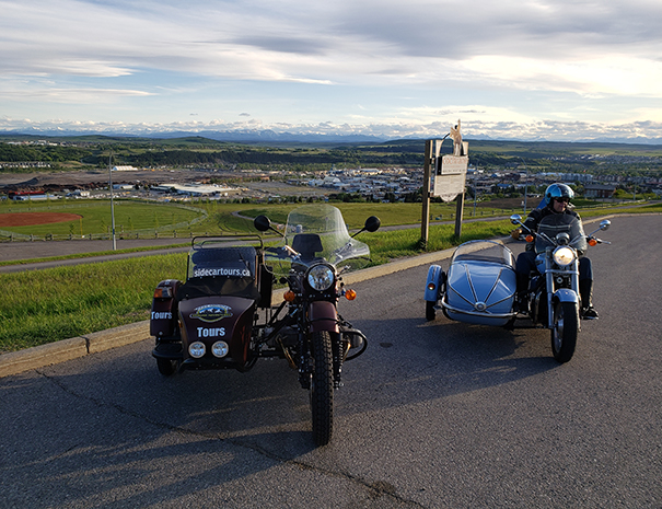 Rocky Mountain Sidecar Adventures tour group in front of Cochrane sign