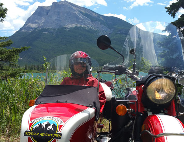 Rocky Mountain Sidecar Adventures Triple C Tour customer in sidecar posing in front of beautiful Rocky Mountain Lake